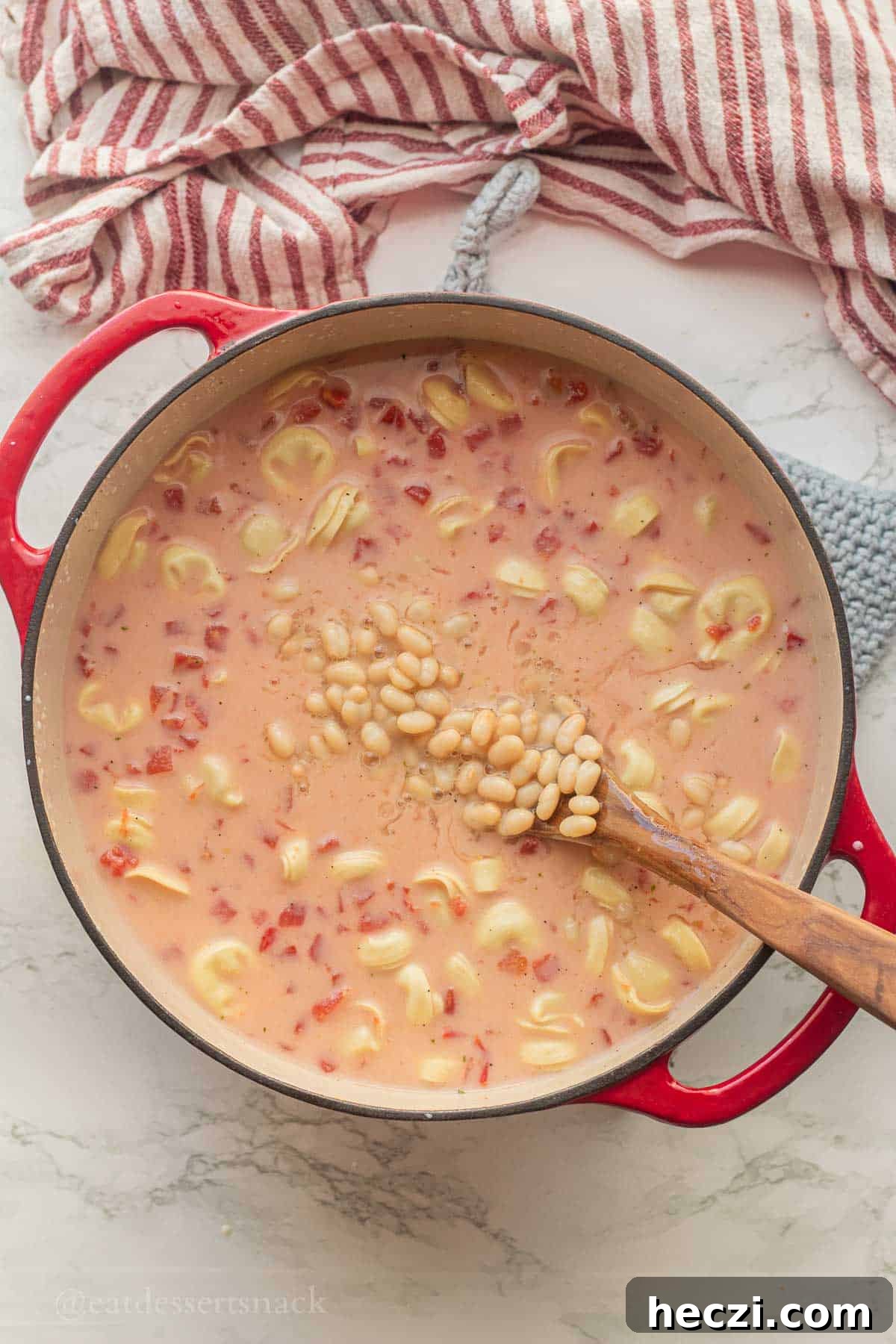 White beans in soup pot with wooden spoon.