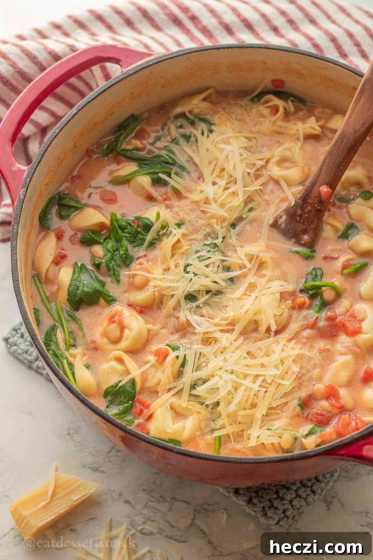 Tortellini tomato soup in pot with wooden spoon.