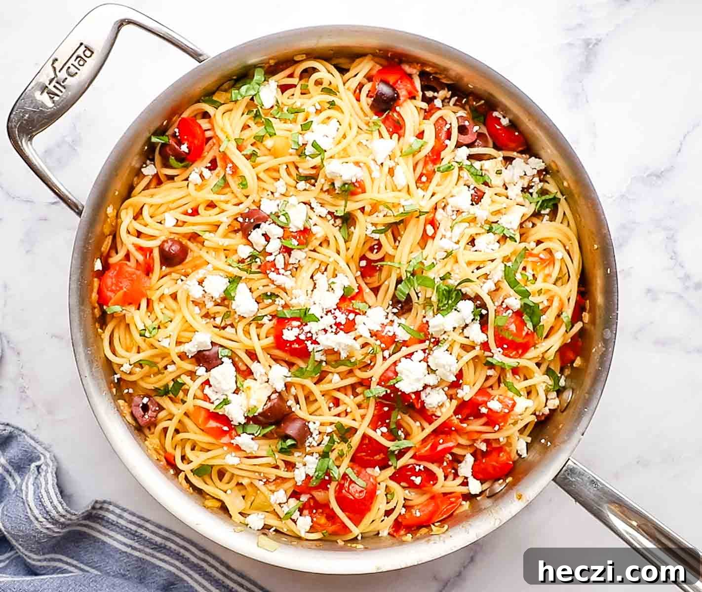 a skilled of greek spaghetti garnished with feta cheese and basil