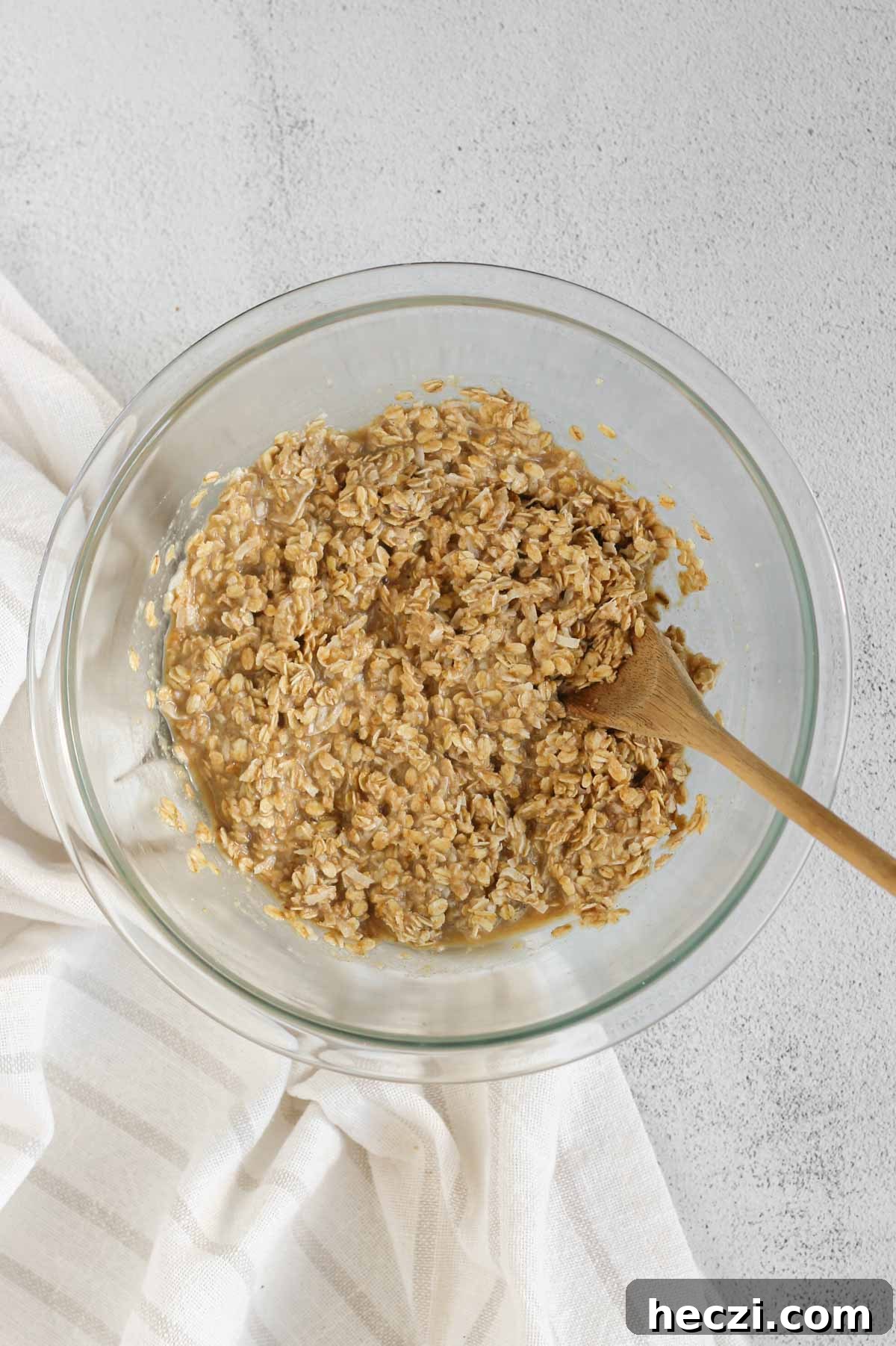 Breakfast cookie mix base in a glass mixing bowl with a wooden spoon.