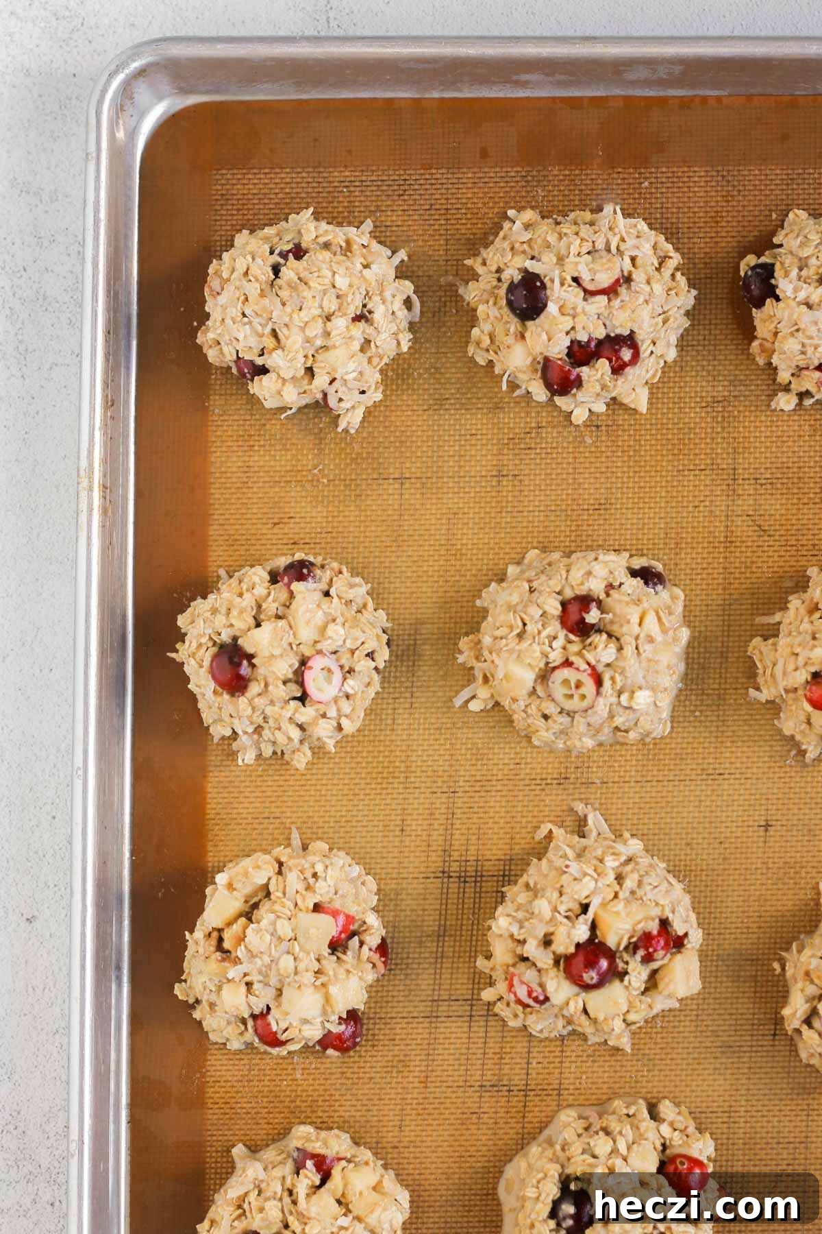 Cranberry apple breakfast cookies unbaked dough on a cookie sheet lined with a silicone baking mat.