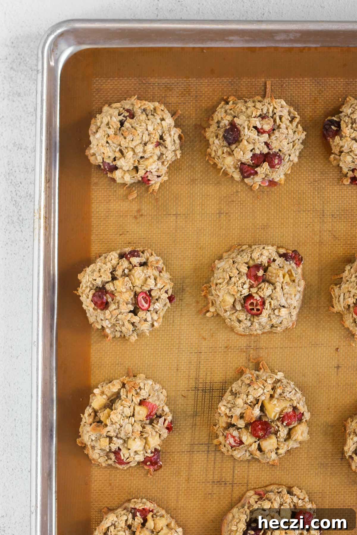Cranberry apple breakfast cookies baked on a cookie sheet lined with a silicone baking mat.