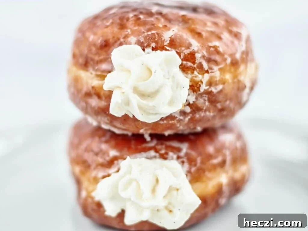 Light and Fluffy Gluten-Free Yeast Donuts Recipe 5 two cream-filled glazed gf donuts stacked on top of each other on white plate.