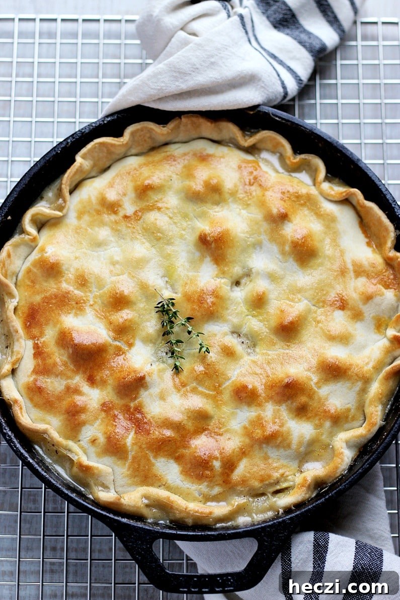 Baked skillet chicken pot pie in a black cast iron skillet with a white and black dish towel.