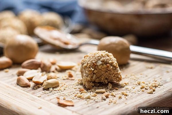 low carb peanut butter balls rolled in chopped peanuts on a cutting board.