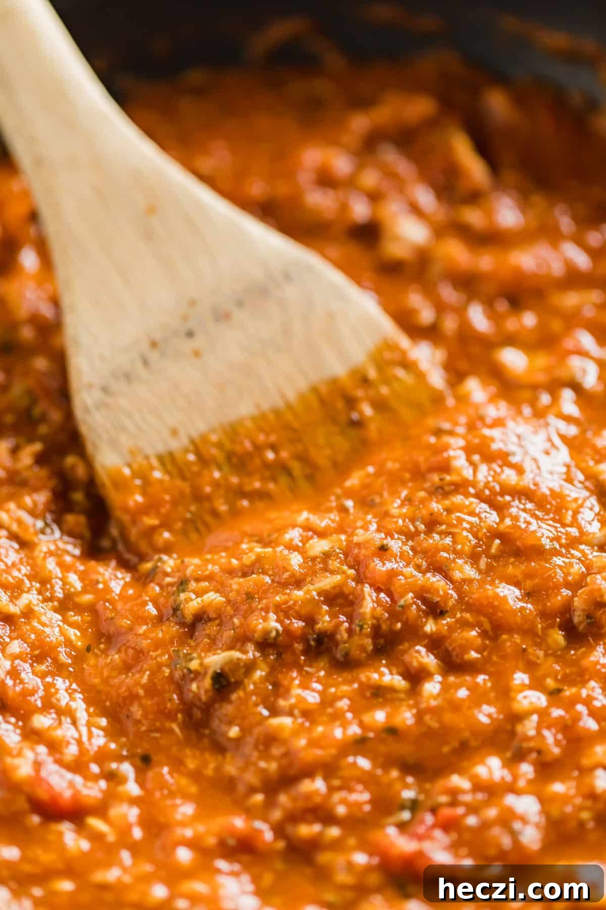 Red Clam Sauce Recipe for Pasta: Simple Italian-Style Sauce 11 A close up of a wooden spoon stirring red clam sauce.