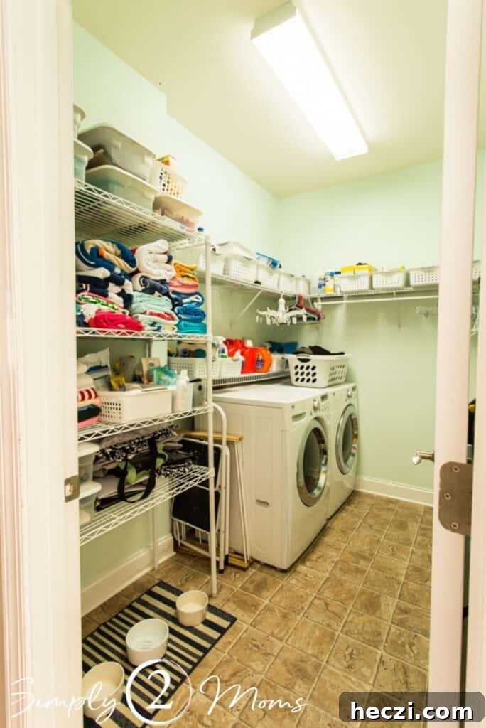 Modern Farmhouse Laundry Room Design Guide: Layouts, Storage & Decor 2 view looking into laundry room from open door washer and dryer on left side of room with wire shelfing above and on wall straight ahead wire storage shelves with towels and bins on left side of room