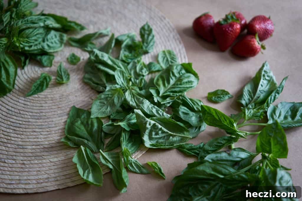 Spring Strawberry and Arugula Salad with Balsamic Glaze 4 Fresh basil lays on a woven placemat and brown butcher paper. Strawberries are in the background.