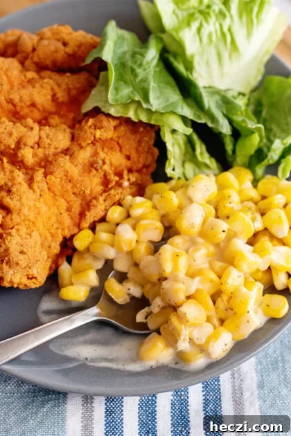 Easy creamed corn on a plate with fried chicken.
