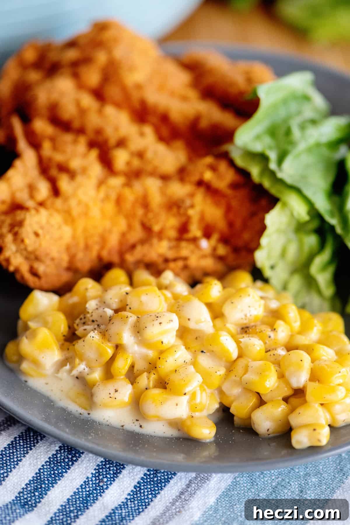Creamed corn with fried chicken on plate.