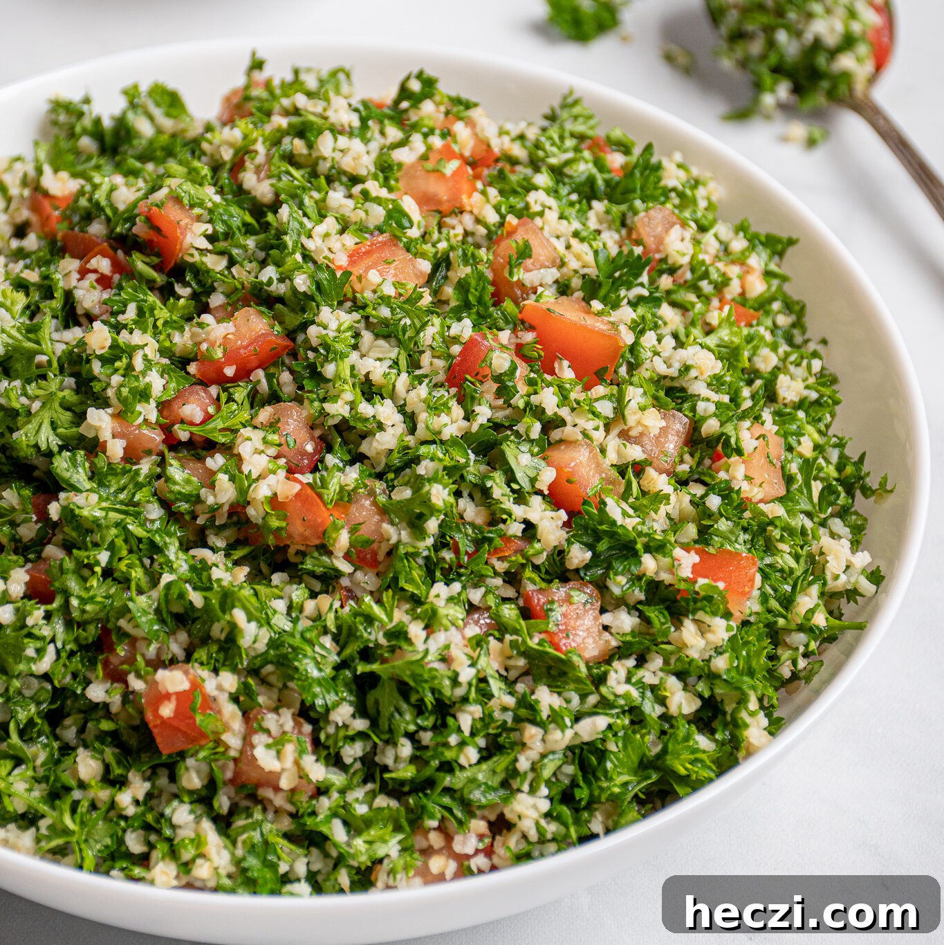 Sheet Pan Chicken Legs with Roasted Sweet Potatoes 10 A large white bowl filled with tabbouleh salad with a spoonful out on the side with parsley leaves falling off.