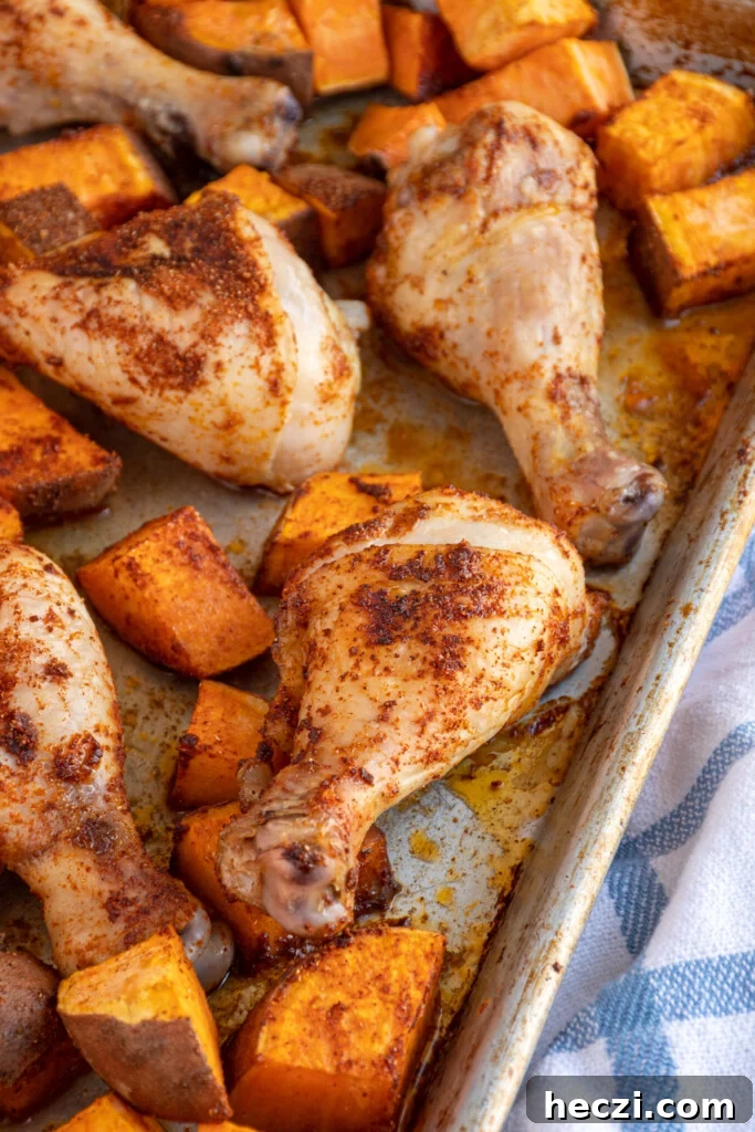 Sheet Pan Chicken Legs with Roasted Sweet Potatoes 3 Close up of a chicken leg on a sheet pan surrounded by sweet potatoes.