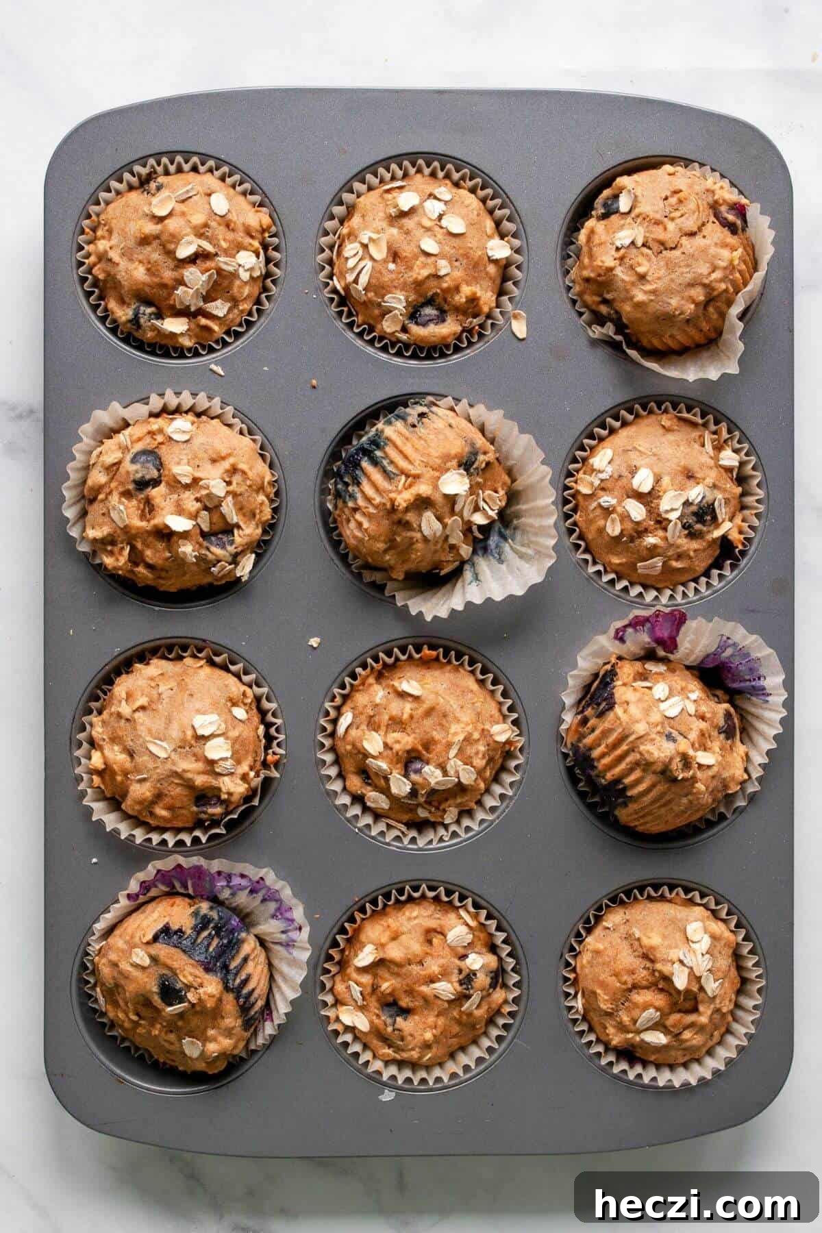 Blueberry Banana Oat Oatmeal Muffins for Breakfast 7 Freshly baked healthy banana blueberry oatmeal muffins cooling in a muffin tin.