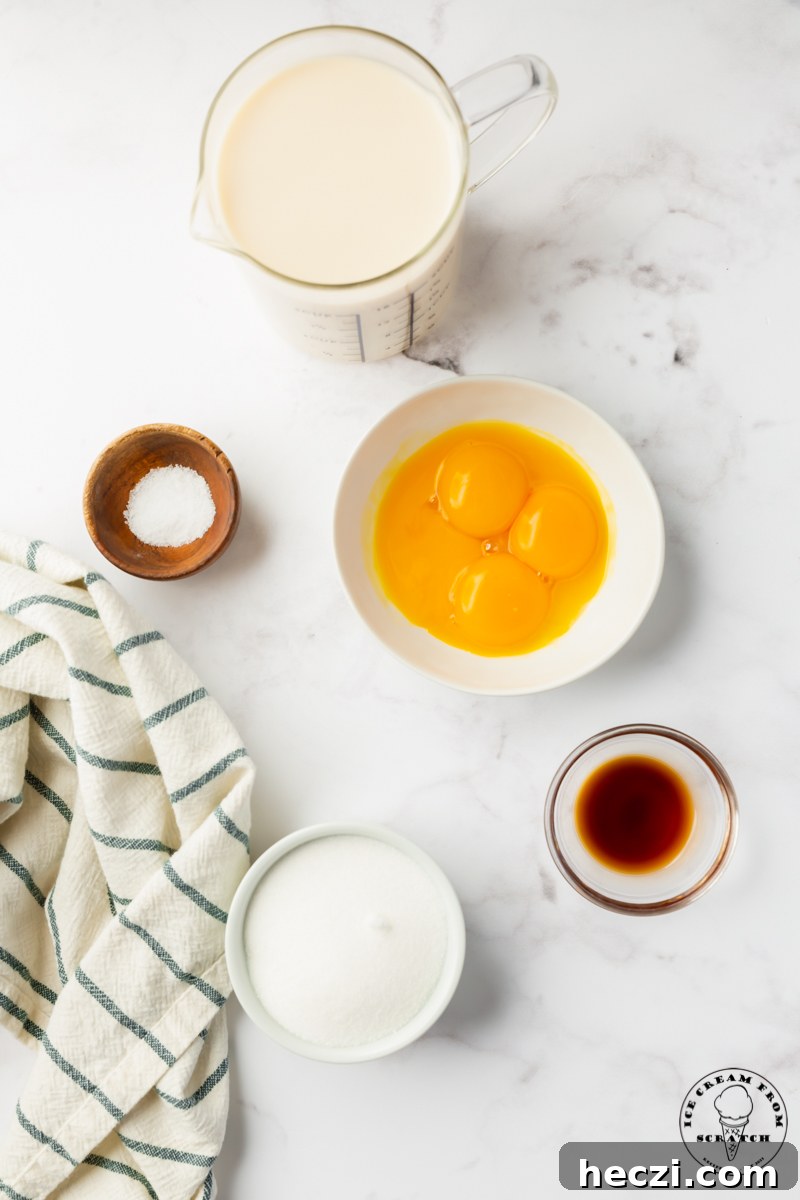 Creamy Oat Milk Ice Cream Recipe — Dairy-Free Frozen Dessert 3 The 5 ingredients needed to make homemade oat milk ice cream, measured into separate bowls on a marble countertop next to a linen striped towel.