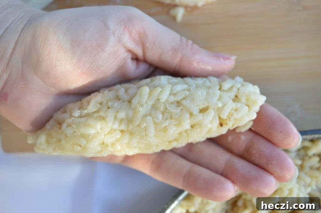 Vegan Supplì: How to Make Italy’s Crispy Fried Rice Balls 6 A hand holding a cigar-shaped rice bundle