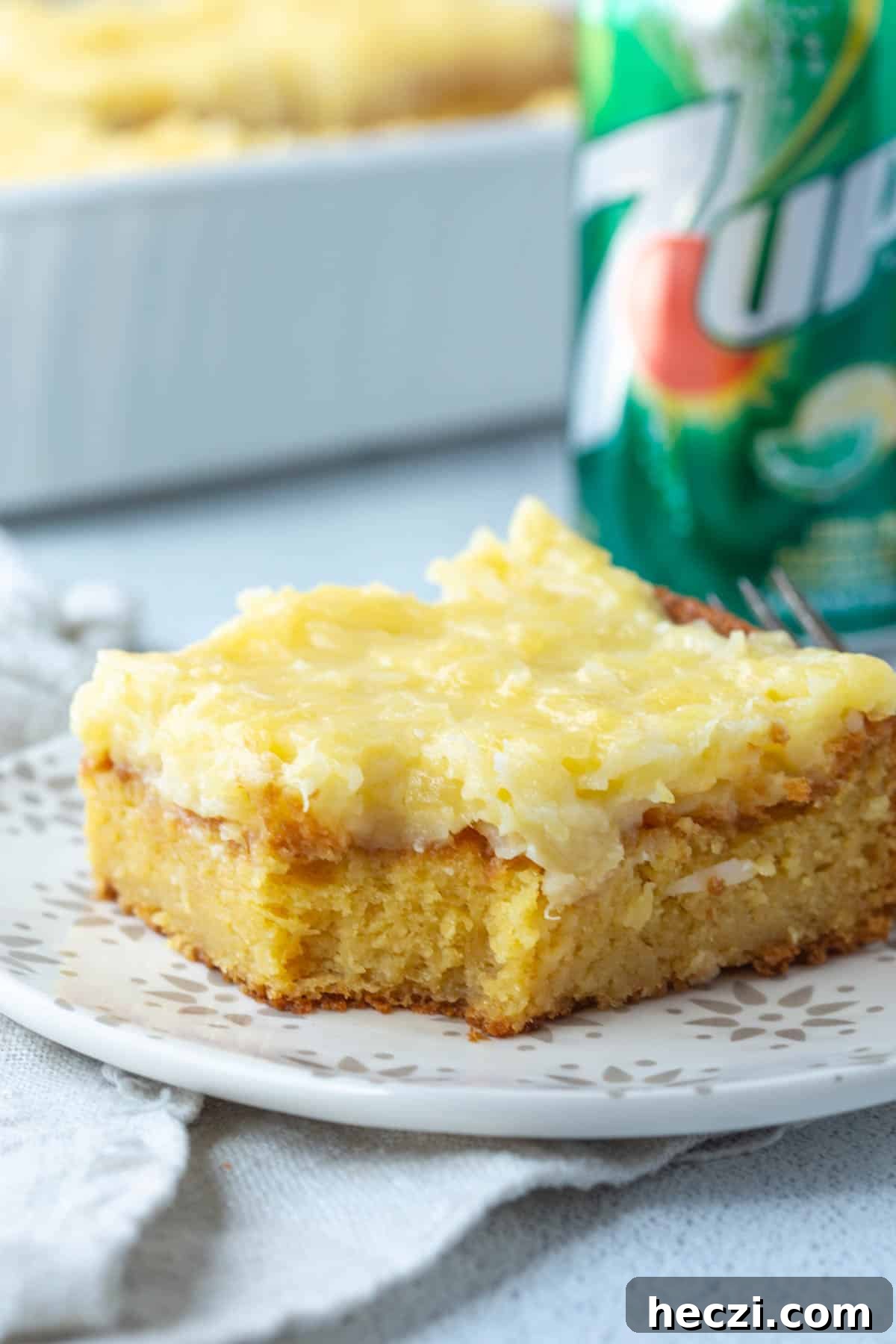 slice of 7up cake topped with coconut pineapple frosting next to a can of 7up.