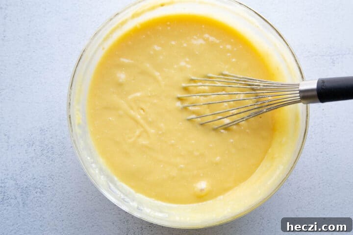 yellow cake batter in a glass bowl with a whisk.