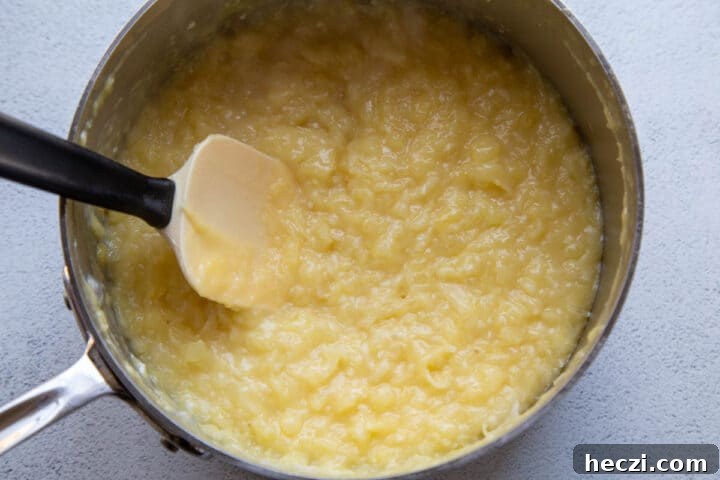 yellow frosting with pineapple and coconut in a large saucepan with a spatula.