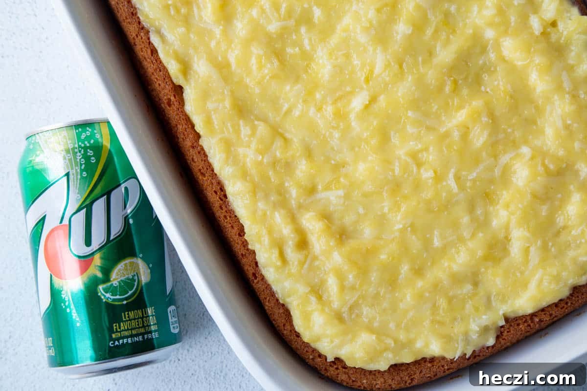 whole 7up cake in a white baking dish, topped with a yellow pineapple frosting, next to a can of 7up soda.
