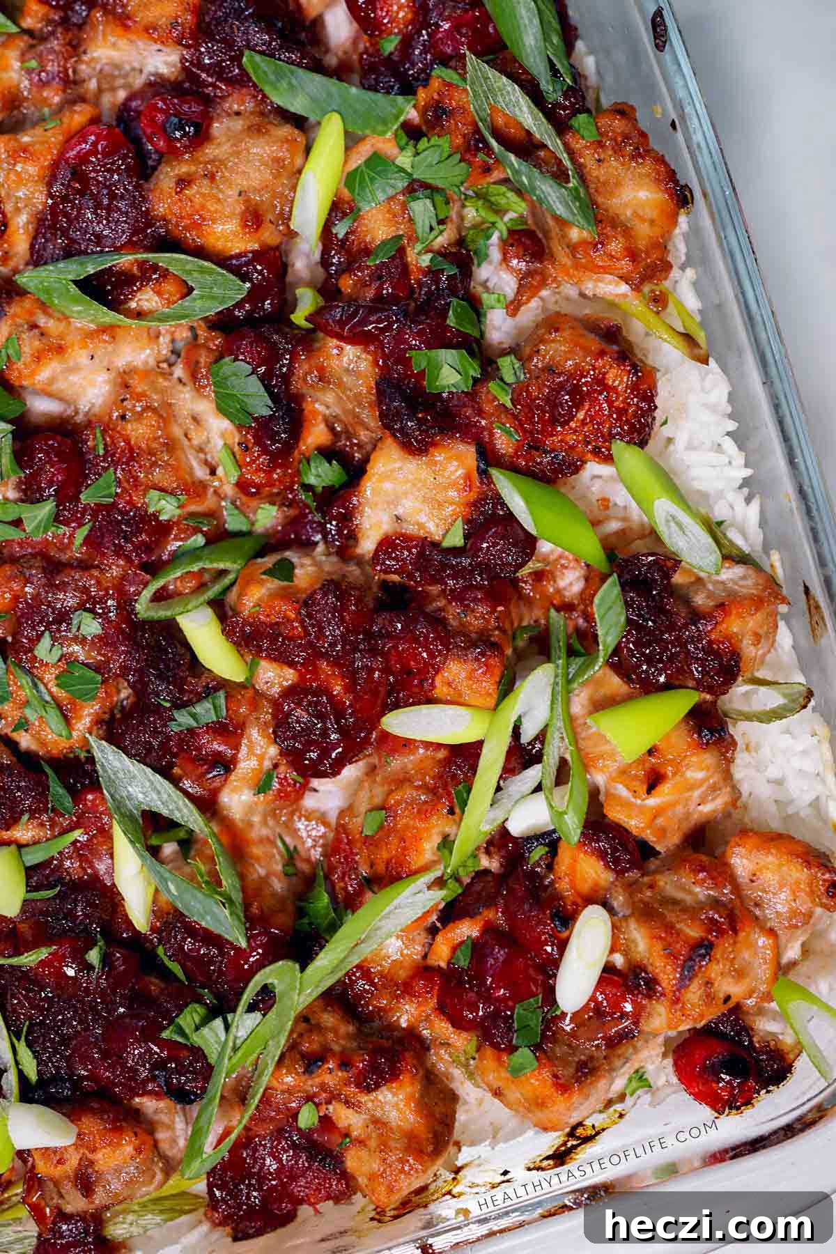 Baked salmon and rice casserole topped with cranberry balsamic glaze and herbs.