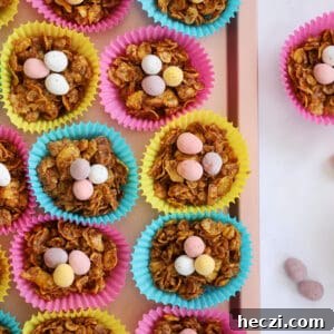 A pink tray of cornflake cake easter nests in colourful cake cases, topped with Mini Eggs.