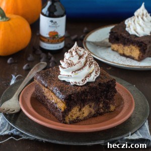 Chocolate Pumpkin Magic Cake Recipe — Moist Layered Dessert 6 A slice of rich chocolate pumpkin cake topped with whipped cream sits on a terracotta plate, with a fork beside it. In the background are another cake slice, a bottle, chocolate chips, and small pumpkins.