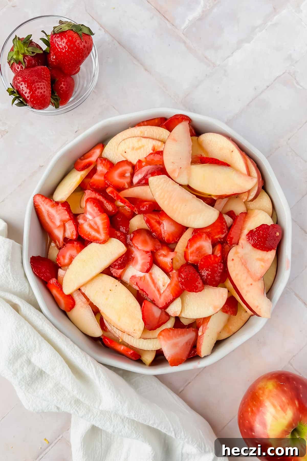 strawberry and apple filling placed in greased pie dish on pink tiled background.