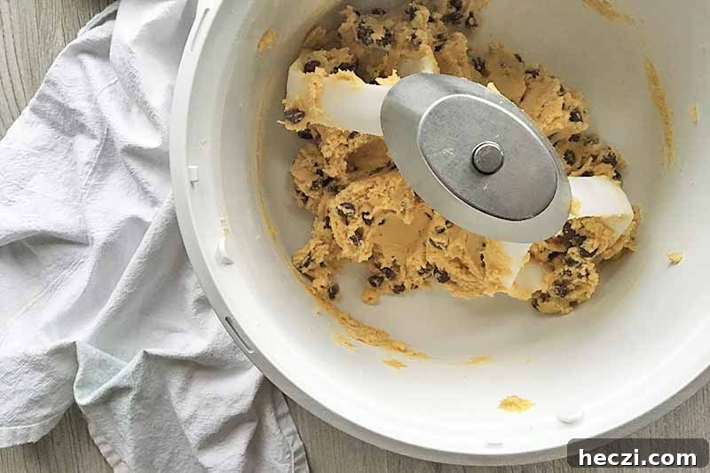 Horizontal image of a white mixing bowl with dough with chocolate chips.