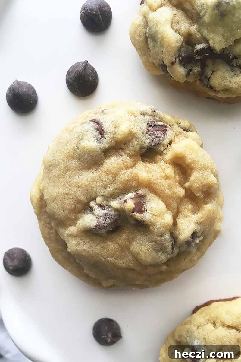 Vertical image of a chocolate chip cookie next to more candies on a white plate.