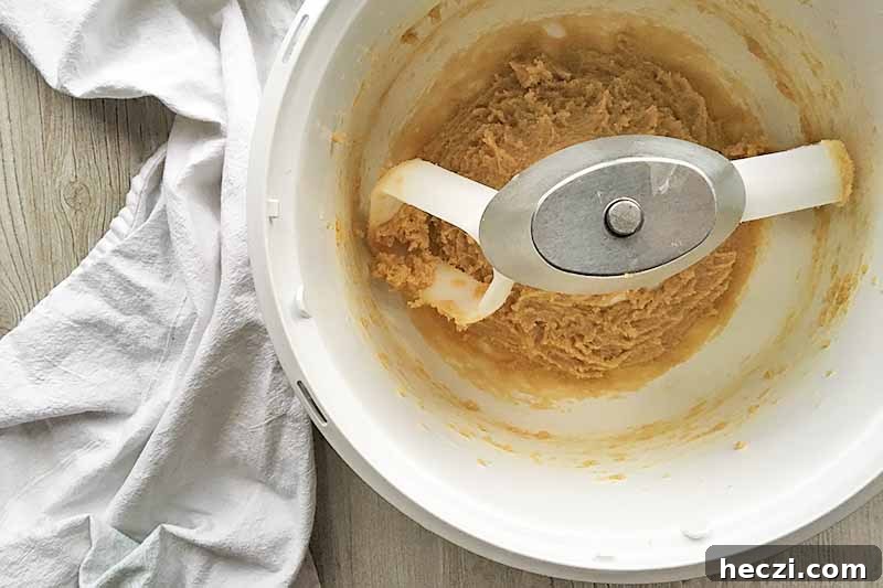 Horizontal image of a butter and sugar mixture in a white mixing bowl.
