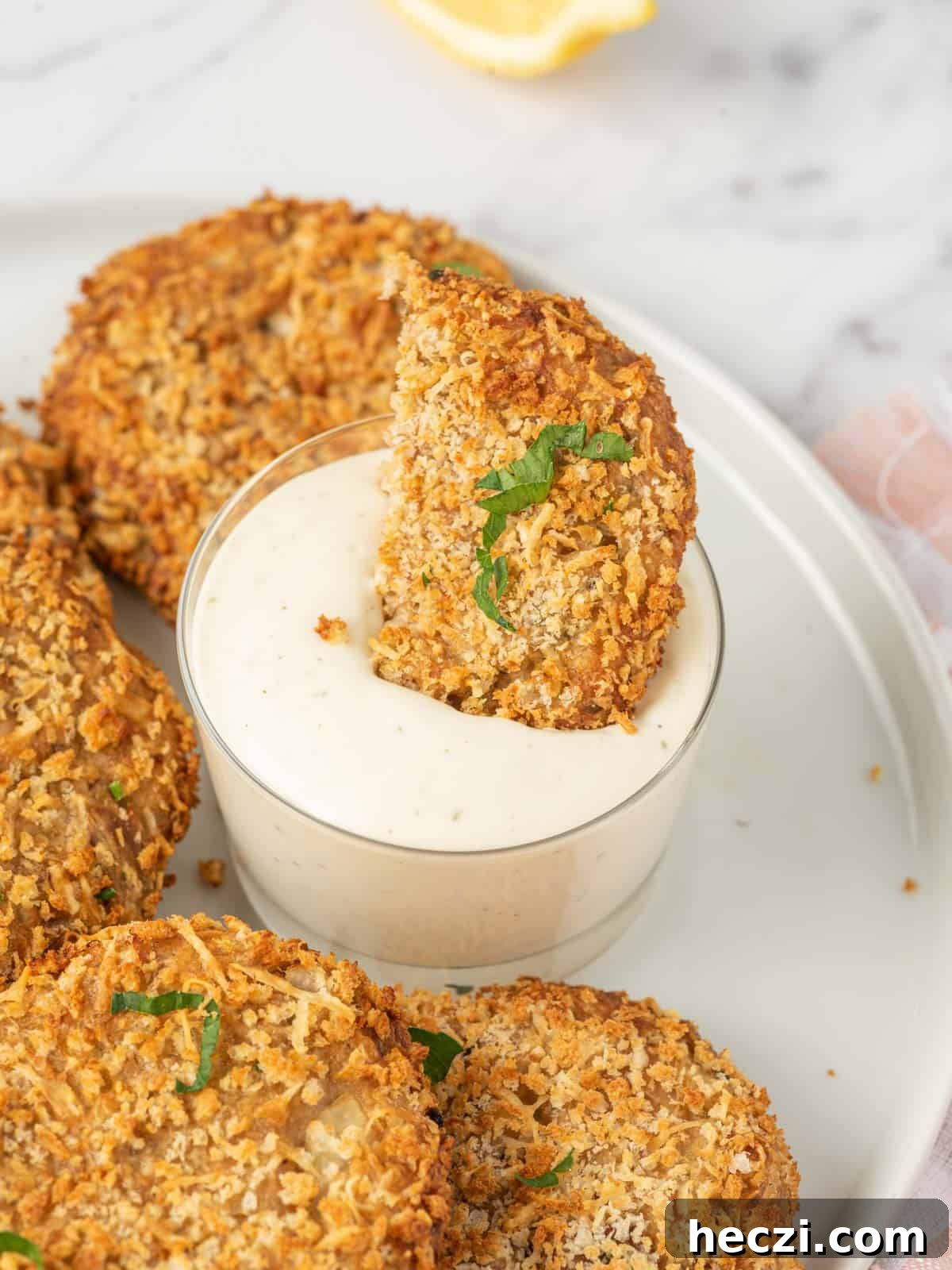 Crispy Parmesan-Crusted Tuna Patties with Lemon Aioli 7 A piece of air fryer tuna patties is dunked into dip.