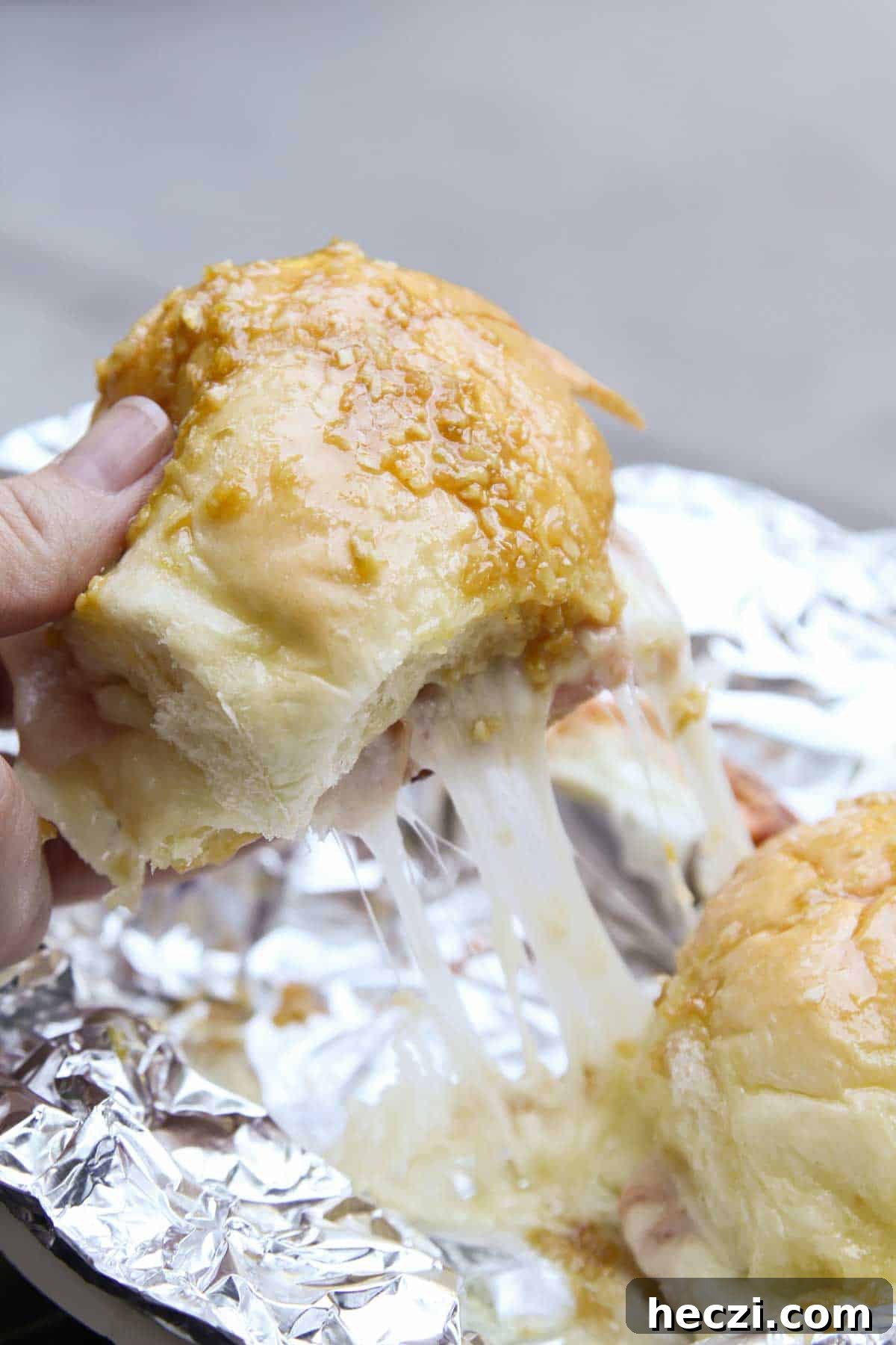 Pulling hot ham and cheese campfire sandwiches apart, showing cheese pull.