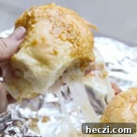 Pulling hot ham and cheese campfire sandwiches apart, showing cheese pull.