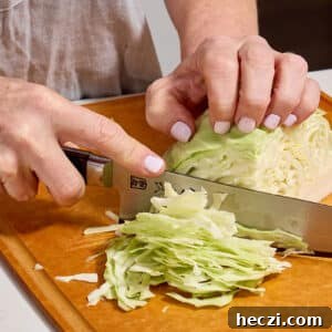 Woman slicing cabbage on cutting board.