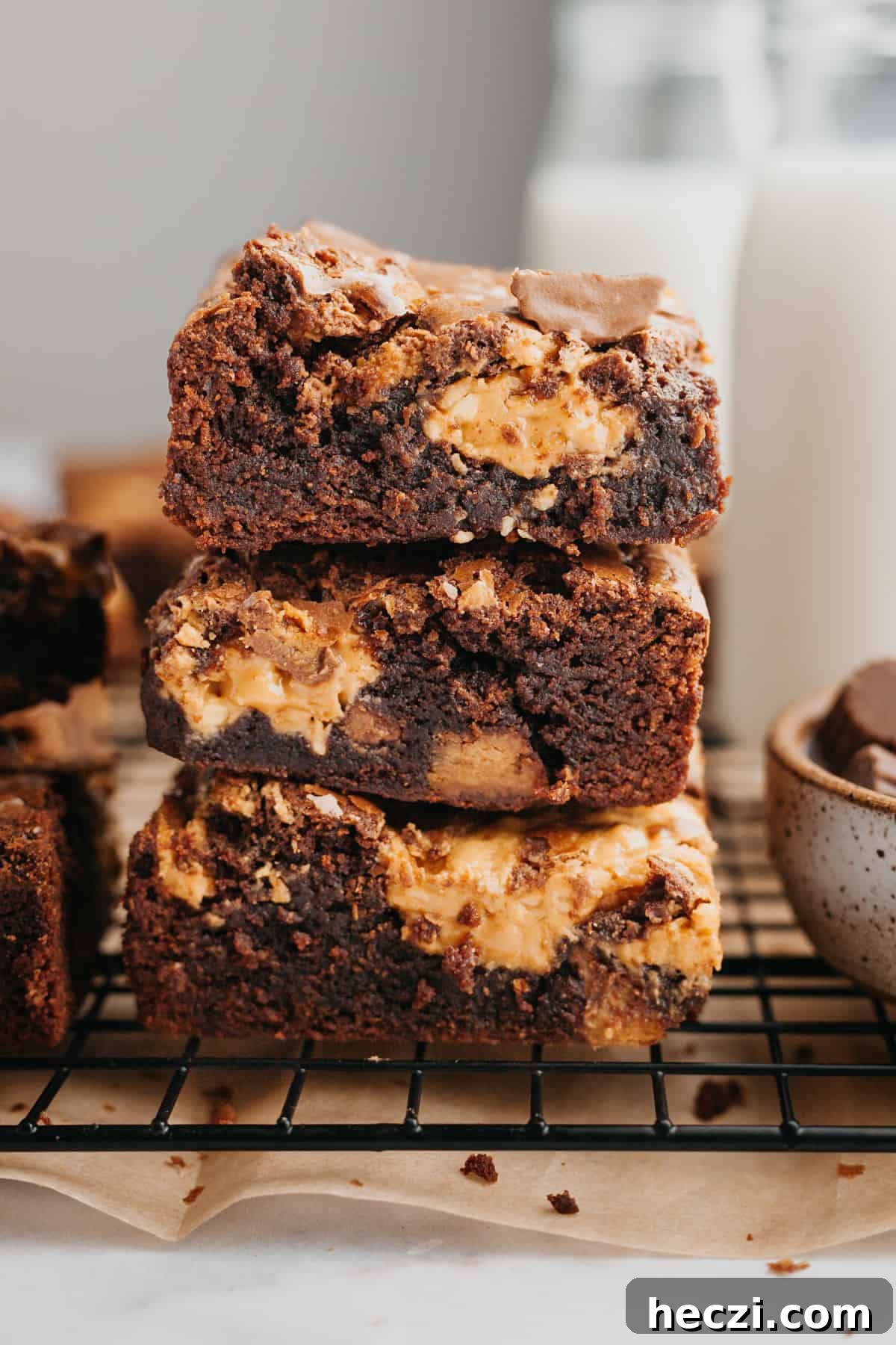 Peanut Butter Cup Brownies: Gooey Chocolate Peanut Butter Bars 6 A stack of three brownies with peanut butter cups.