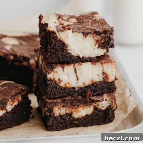A stack of three cheesecake brownies on a silver baking tray.