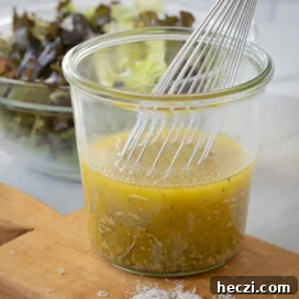 Homemade Italian Dressing Recipe: Classic Flavor in Minutes 11 Golden Italian salad dressing in a jar with a silver whisk.
