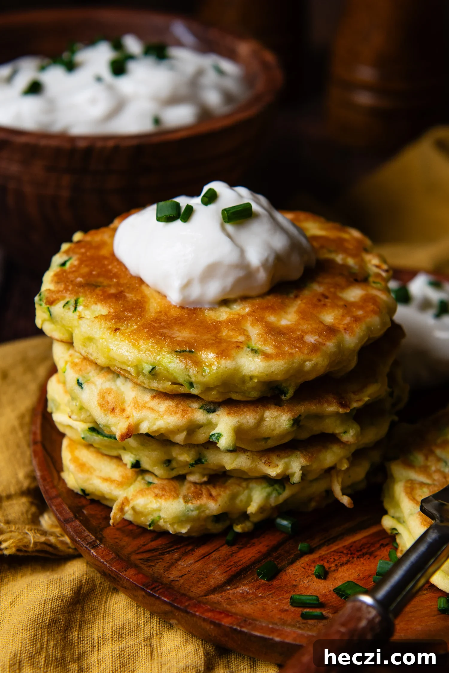 a stack of GF zucchini fritters with sour cream on top.
