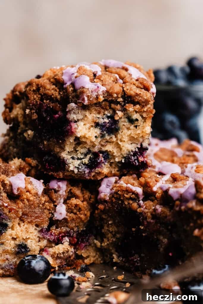 Blueberry Coffee Cake Recipe with Streusel Crumbs 2 A slice of blueberry coffee cake with bites missing, stacked on top of other slices.