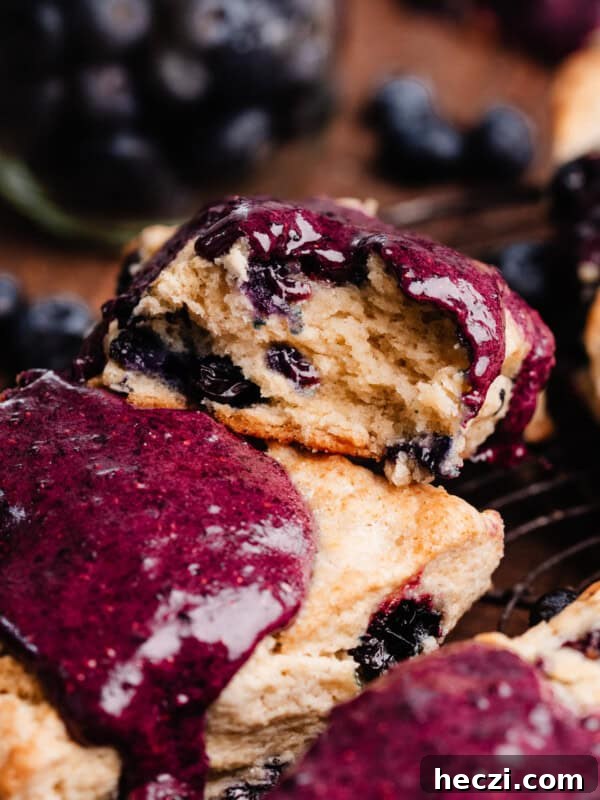 Blueberry Coffee Cake Recipe with Streusel Crumbs 14 A close-up on a blueberry glazed scone with a bite missing, showing the tender, flaky layers inside.
