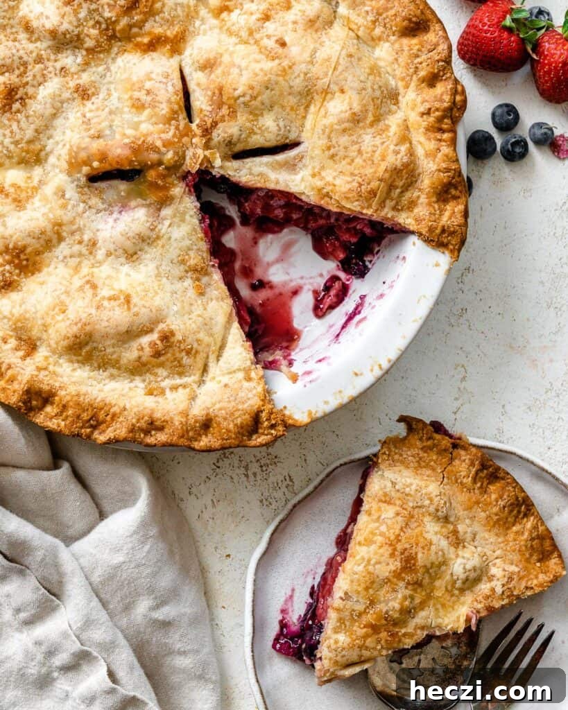strawberry blueberry pie with a slice cut out of it. 