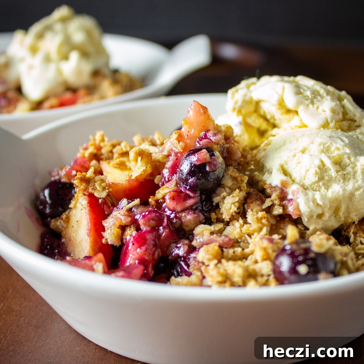 a bowl of apple blueberry crisp with ice cream. 