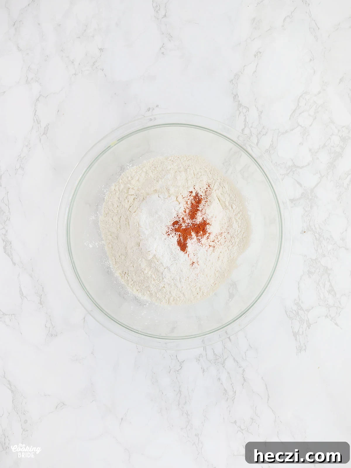 glass mixing bowl with white cornmeal, all-purpose flour, baking powder, and cayenne pepper