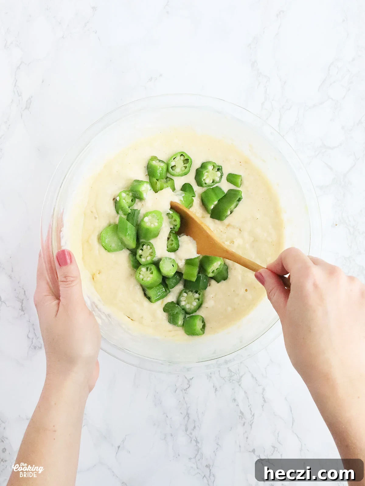 hands stirring okra into the hoe cake batter,