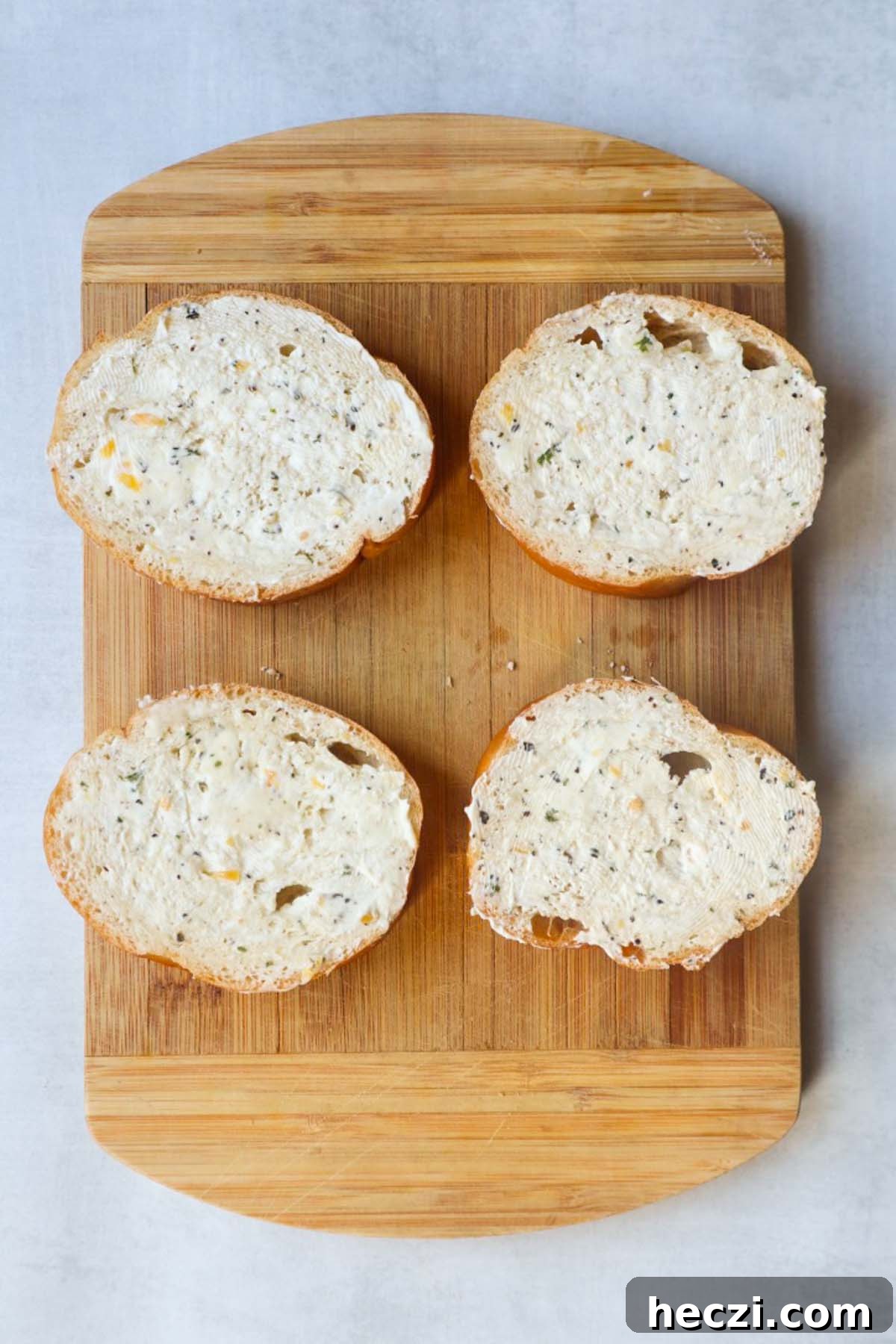 wooden cutting board with four slices of french bread topped with garlic herb butter