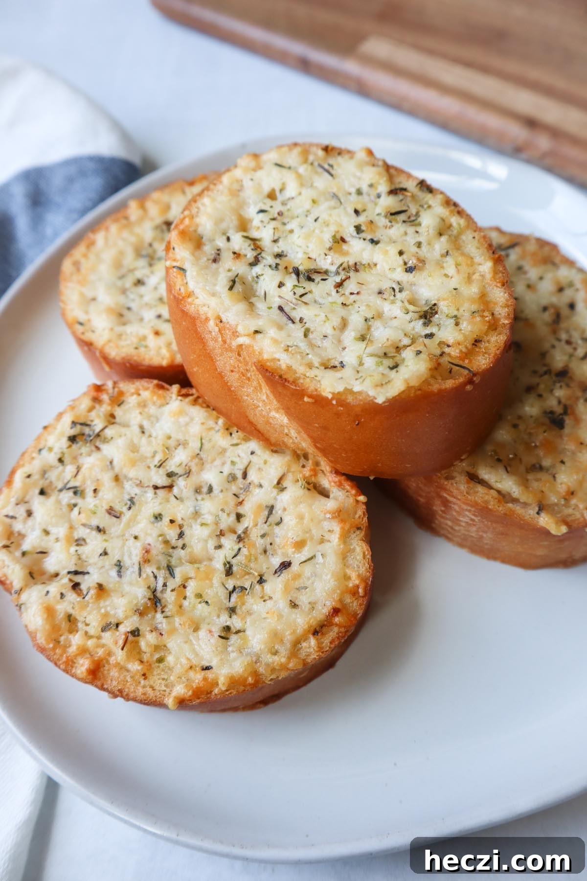 white plate with four slices of french bread topped with cheese, butter, and italian seasoning