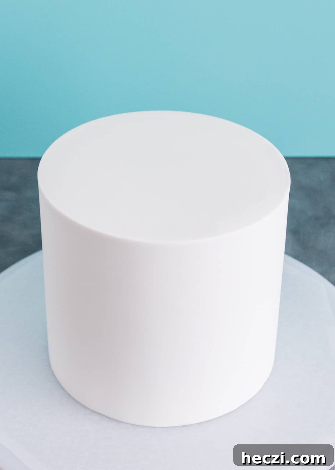 Close up of the top of a white cake wrapped in fondant showing the seam around the top edge.