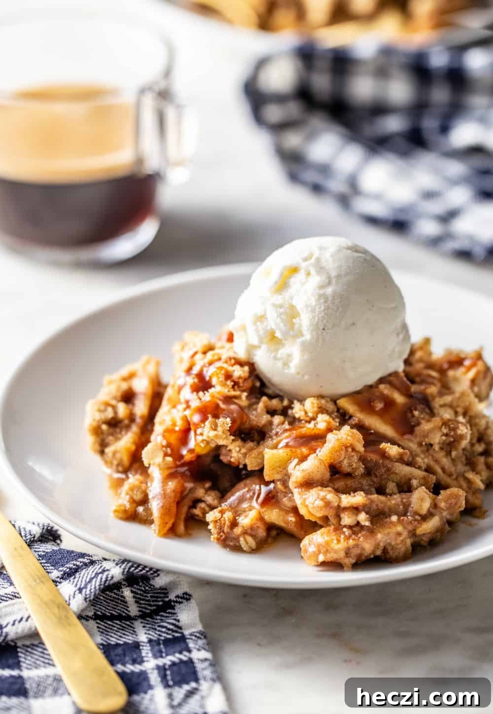 Warm Caramel Apple Crisp with Crunchy Oat Topping 2 Caramel apple crisp topped with a scoop of vanilla ice cream on a white plate