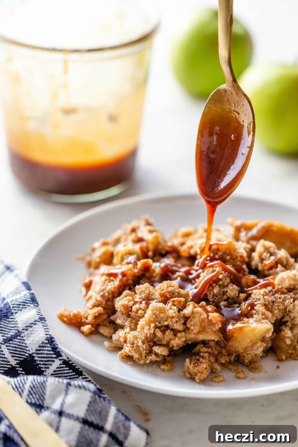 Warm Caramel Apple Crisp with Crunchy Oat Topping 3 Spoon drizzling caramel sauce over a plate of caramel apple crisp