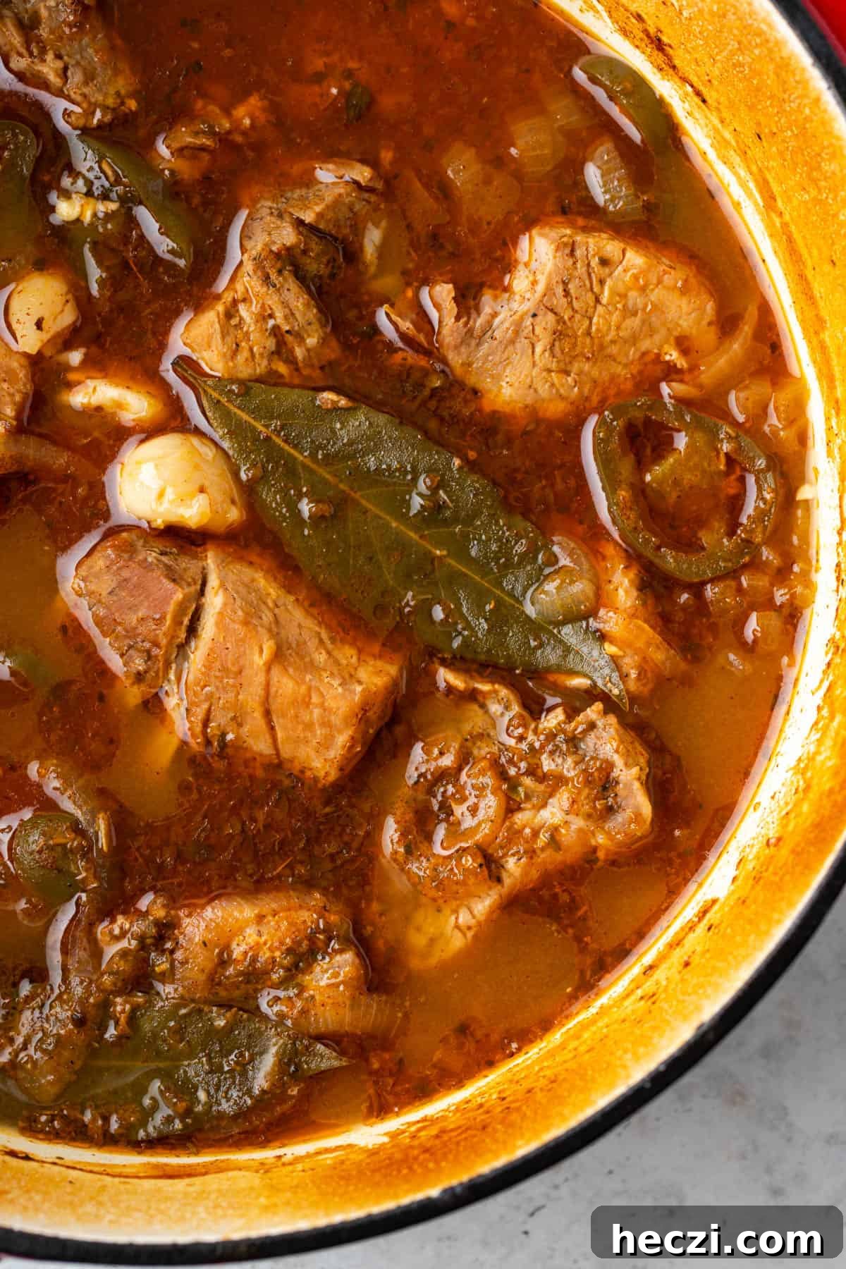 Cooked pork and vegetables in sauce inside a dutch oven pot.